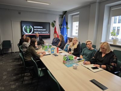 Zdjęcie przedstawiających uczestników spotkania siedzących przy stole konferencyjnym w sali.